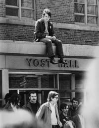 Protester sits over the doorway of Yost Hall