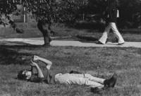 Student lounges on the grass playing a recorder