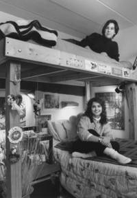 Two women relax on their loft beds