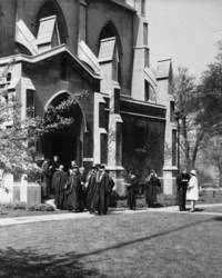 People in academic gowns gather outside of Stone Chapel